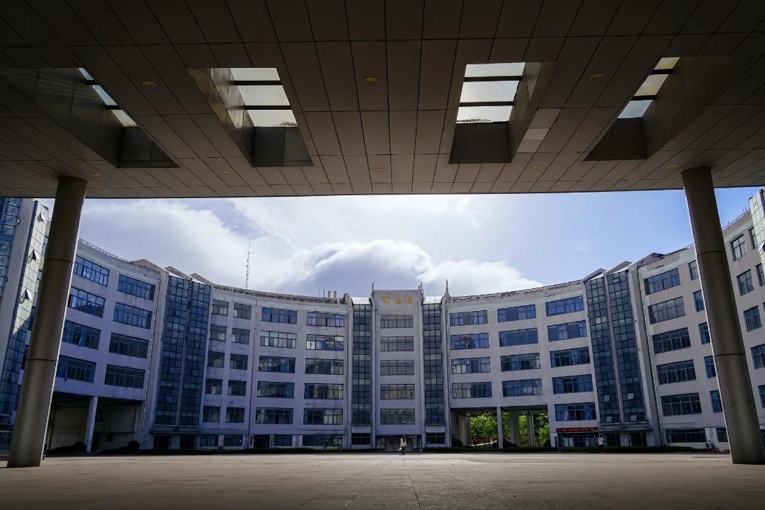 Curved university courtyard building under a blue sky